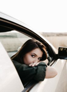 pensive woman sitting in car and looking at camera