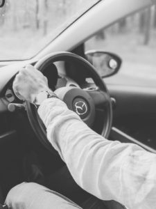 person wearing white long sleeve shirt while holding steering wheel